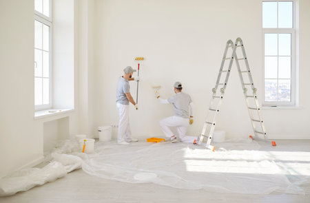 Painters team wall painting, construction workers, professional service near stepladder wearing protective uniform ready for preparation, painting, finishing tasks for room repair, interior designの写真素材