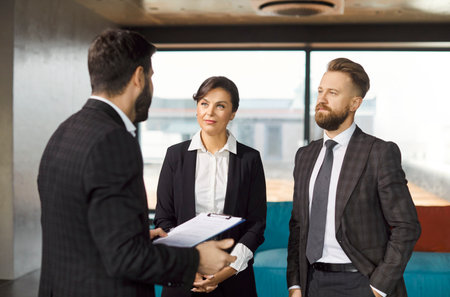 Business people listen intently to colleague as he shares details about important work project. Male...