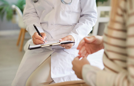Doctor writing in clipboard close up, female patient consulting woman gynaecologists, endocrinologists, private GP specializing in female care health, contraception, family planning in clinicの写真素材