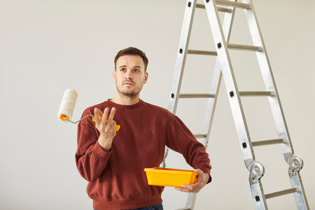 Painter thinking about repair problems, construction worker painting walls with paint roller brush, problems with finishing task for room, building repair worryの写真素材