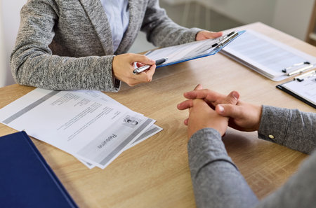 Interview recruitment in office manager meets candidate. HR manager checks documents, noting experience and fit, and discusses eligibility with applicant job seeker. Hiring and employee recruit.の写真素材