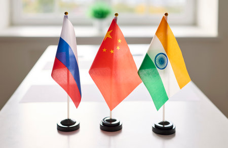 Flags signal diplomacy during a meeting table negotiation. Three desk flags of Russia, China, and India stand on a conference table for cooperation. Clear concept: international diplomatic meeting.の写真素材