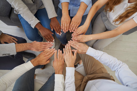 Team of diverse business people holding their hands together. Group of multiracial men and women huddling and joining hands. Cropped shot. Top view, shot from above. Teamwork and support conceptの写真素材