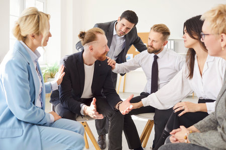 Diverse people group gathered in circle at workplace office, share, discuss work or problems, giving psychological support, helping, plan strategy, interacting with sympathy on psychotherapy trainingの写真素材