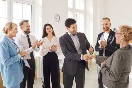 Team of diverse coworkers shaking hands and celebrating success during a meeting in the office. Agreement, partnership, and teamwork, showcasing the joy of achieving a shared deal.の写真素材