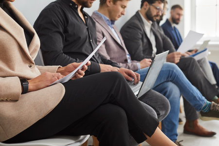 Cropped shot of business people waiting for their turn to job interview. Focused people sitting by...