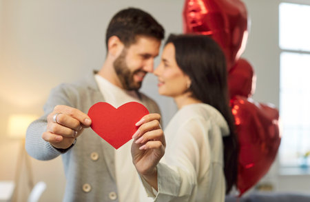 Red heart love symbol, loving happy Valentine day couple date, affectionate people, close in hug, kiss, showing romantic moment feeling sharing kind emotion, holiday balloon decoration interior designの写真素材