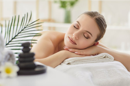 Relaxed woman lies in salon during spa treatment or back massage, experiencing body care and therapy with satisfaction in a professional setting with focus on relaxation and wellness.の写真素材