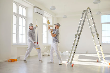 Happy man painter team dancing together during work on house renovation at home, refreshing apartment in a joyful setting with focus on creativity and teamwork in a lively environment.の写真素材