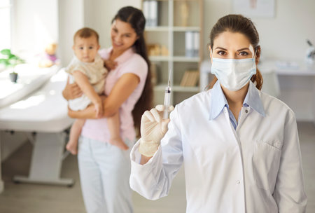 Nurse or pediatrician holds syringe for baby vaccination. MFamily doctor prepares a dose as mother holds child in medical pediatric clinic, ensuring healthcare. Concept child immunization and safety.の写真素材