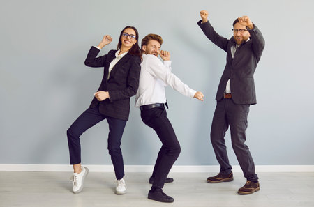 Happy business team celebrating success or just having fun. Group of three funny, joyful, young...
