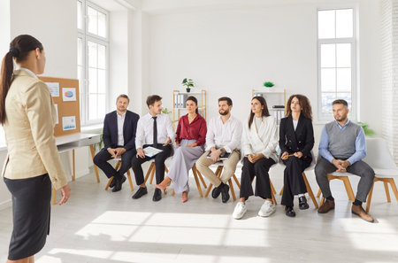 Businesswoman conducting a meeting and conversation with a group of business people or office staff. Showcasing teamwork, leadership, and professional team collaboration in the workplace.の写真素材