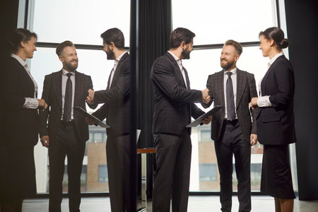 Group of business people making commercial deal agreement, meeting for negotiating, posing in spacious office room. Real estate agent welcoming clients at boardroom, discussing rent issuesの写真素材