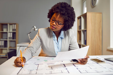 Female architect developing and drawing architecture project on paper. Young Afro American woman in...