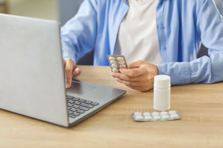 Woman with pills and laptop searches medicine description, side effects and treatment options. The scene shows online healthcare, drug guidance and digital consultation. Safe use requires knowledge.の写真素材