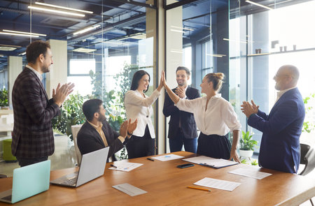 Photo of corporate workers gathering together in office room, reaching agreement, making hand shake,...