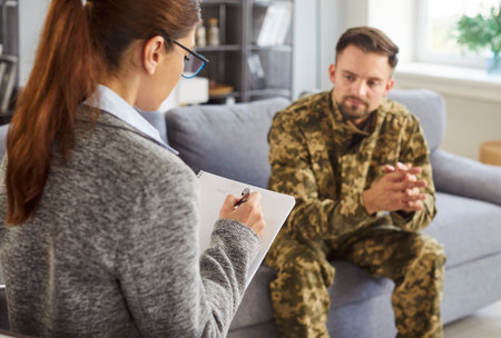 Young soldier man wearing military uniform meets with professional therapist to work through post-traumatic stress disorder or PTSD and emotional scars left by war. Mental problem recovery conceptの写真素材