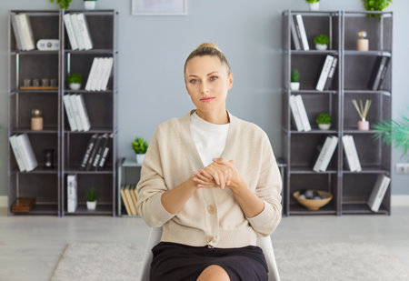 Portrait of confident businesswoman in office, serious woman sitting on chair on online business meeting. Young professional saleswoman and expert looking at camera. Video call, presentation conceptの写真素材