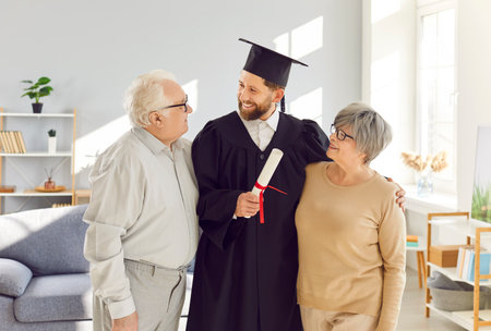 Happy family at home close celebrating adult son graduation awarding of diploma, senior old parents children, conferring of university, college degree, achievement grandson wearing gown and capの写真素材