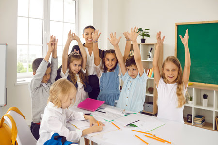 Group of happy little children having fun in class. Cheerful, joyful teacher and elementary students...