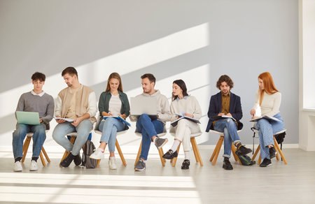 Business people or students in team sit in row on gray background, working and learning with collaboration, showcasing teamwork and partnership in office setting with focus and dedication.の写真素材