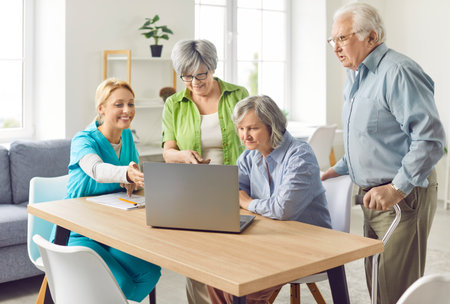 Senior group and caring kind nurse, geriatric medicine caretaker helping with laptop for nursing home residents, senior adult in assisted living, female doctor visiting patient, caregiving serviceの写真素材