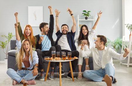 Portrait of excited happy young friends sitting on sofa in living room watching sport football match...