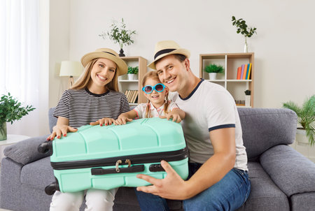 Family tourist summer vacation happy packing suitcase together at home laughing planning, preparing for travel, recreation, parents, daughter dreaming of enjoyment, sea, going on leisure trip, journeyの写真素材