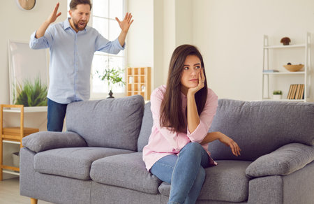 An angry man at home yells at a woman who turns away indifferently. The concept of misunderstanding in family relationships. Abuse, conflict and emotional stress. Scandal and controversyの写真素材