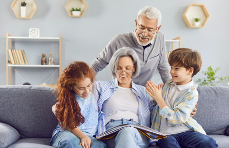 Portrait of a happy grandparents reading a book to their grandchildren or looking through a family...