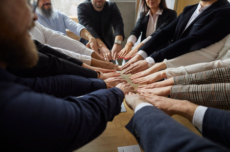 Group of business people men and women holding hands together. Working team putting hands in circle. Teamwork, community, team building training exercise, unity, cooperation and mutual help concept.の写真素材