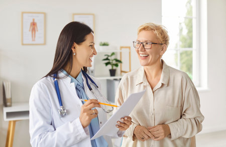 Doctor or nurse provides medical consultation to an elderly patient in a hospital office. Healthcare conversation focuses on patient needs, offering guidance and support in a professional environment.の写真素材