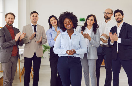Female leader at head of team enthusiastically applauding, showing support and camaraderie. African...