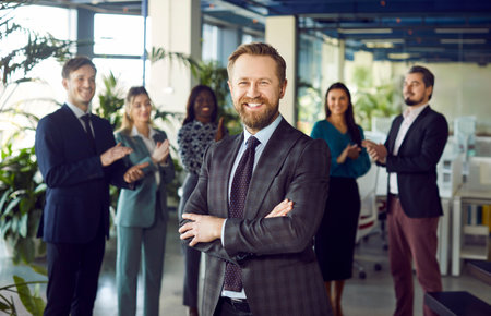 Happy young businessman in formal suit portrait, smiling confident guy posing for photo, looking at camera, diverse business team applauding for coworker success, congratulating promoted colleagueの写真素材