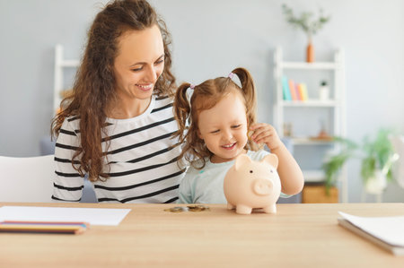 Mother and child save money together, putting a coin into a piggy bank at home. This family activity promotes values of wealth and responsibility, creating meaningful shared experiences.の写真素材