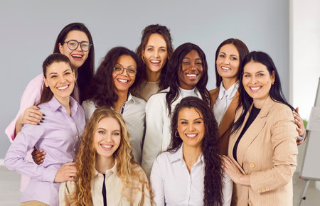 Portrait of group of happy cheerfull young diverse women friends or coworkers and company employees looking at camera posing and smiling together on grey background. Diversity, friendship concept.の写真素材