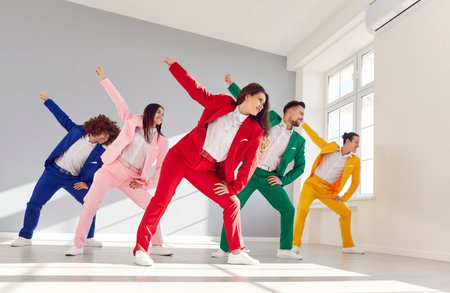 Dancing friends team, group of happy people in vibrant vivid formal suit, cool dance, office party fun. Young cute disco in color suit set wear, express enjoyment, colorful mood, event or performanceの写真素材