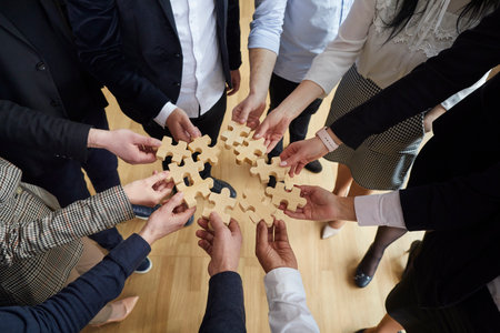 Hands of office workers man and woman in business clothes with puzzle pieces symbolize team building and ability to work together to achieve company goals or corporate partnerships standing indoorsの写真素材