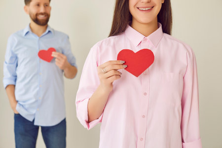 Holding paper hearts love couple share moment of pure love. Simple gesture of love captures essence of their bond portraying beautiful picture of devotion connection with big love of man and womanの写真素材