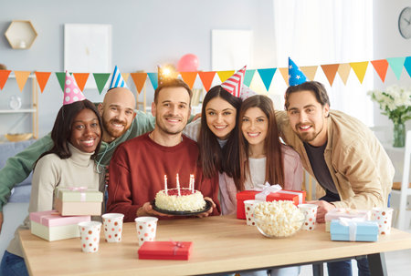 Happy birthday candle cake celebration, friendly group portrait, young friends party together for...