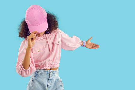 Child shows something on blue blank copyspace studio background. Pretty kid invites you to see new...