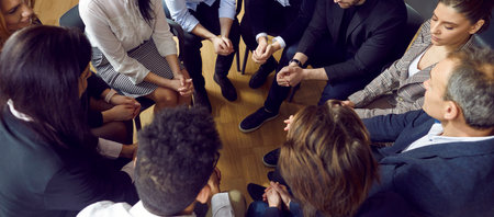 Cropped high angle shot of solid business team during work meeting in office. View from above of diverse group of young and mature people sitting in circle at corporate meeting. Teamwork conceptの写真素材