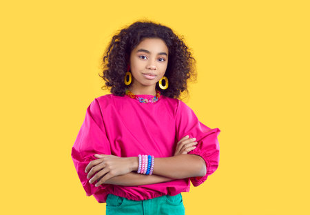 Beautiful African American millennial girl in colorful clothes isolated on yellow studio background posing. Pretty ethnic black young woman model. Fashion and style concept. Crop shot.の写真素材