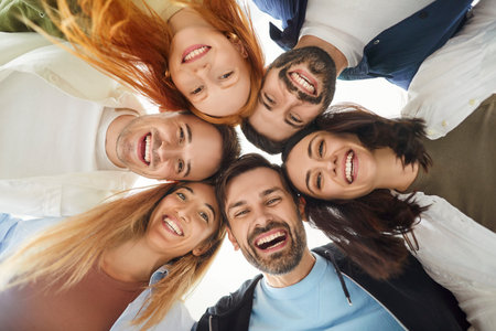 Portrait of a group of happy friends stands in a circle, laughing together in a positive moment. Fun...