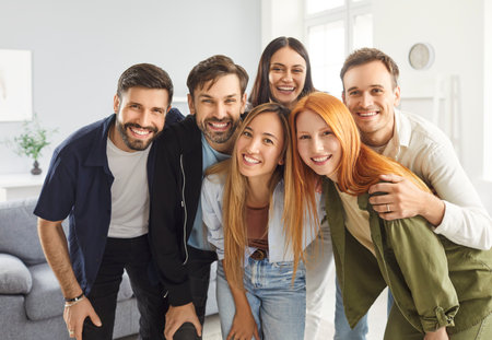 Group portrait of happy friends embraces during a party at home. Laughter, friendship, and togetherness, highlighting the joy and connection shared among the people crowd during the celebration.の写真素材