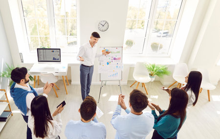 A group of business people in the office listen to a speaker near a flipchart. Concept discussion of...