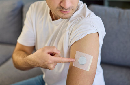 Man with diabetes patch sensor on arm. He points to a wearable glucose monitor, highlighting modern...