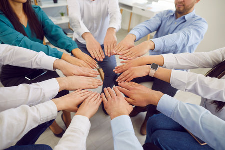 A group of business people stretched out their hands, joining them in a circle, close-up. Concept of team unity and joint efforts. Collaboration between employees and community supportの写真素材