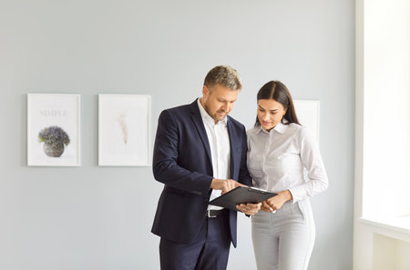 Portrait of young confident man professional realtor standing with female client in modern new...