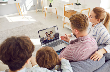 Happy young family with two boys children sitting on sofa in the living room at home and having...